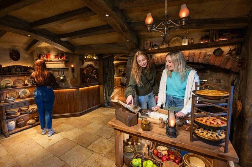 A rustic kitchen with wooden beams, a stone floor, and a wooden counter with food items. 1