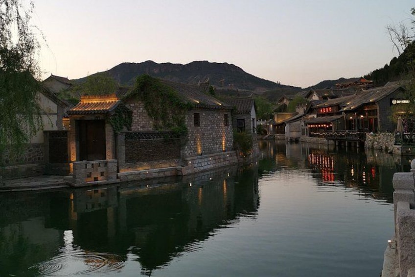 Un tranquilo pueblo a orillas del río, con arquitectura tradicional, aguas serenas y colinas al fondo. 4