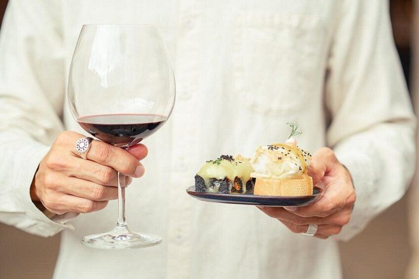 A person holding a wine glass and a plate with food. 2