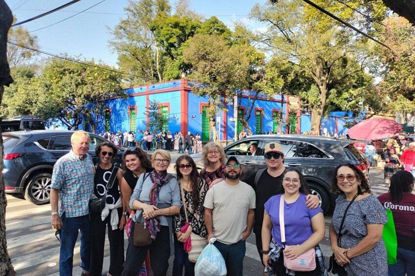 A group of people posing for a photo in an outdoor setting with colorful buildings and trees in the background. 3