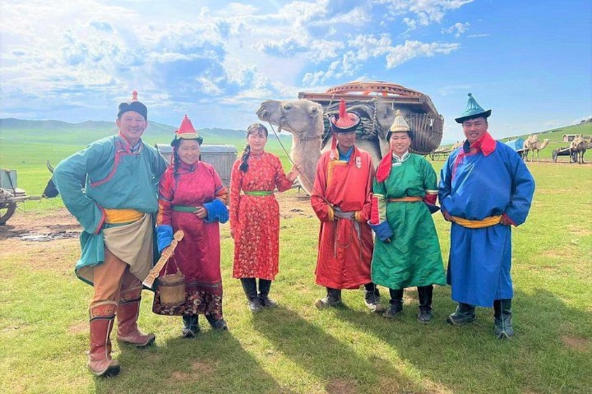 Een groep mensen in traditionele kledij staat op het gras, met een groot vliegtuig op de achtergrond. 5