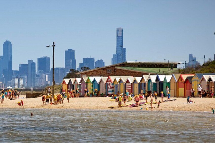 A beach with colorful beach huts and a city skyline in the background. 3
