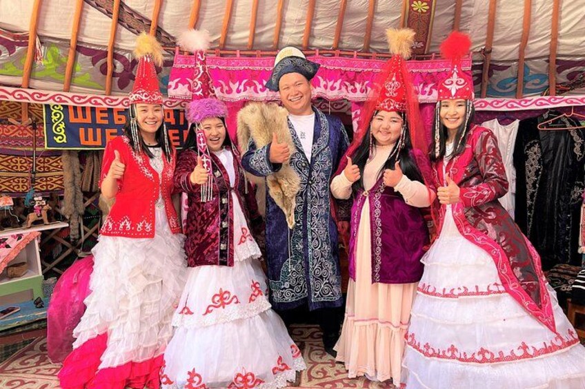 A group of people in traditional attire, a tent, and various cultural items. 1