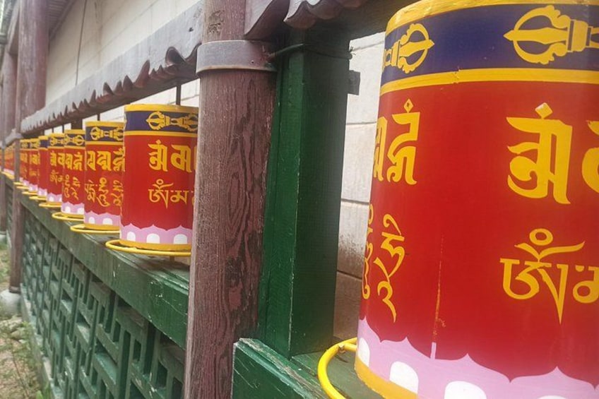 A row of prayer wheels with colorful inscriptions. 5