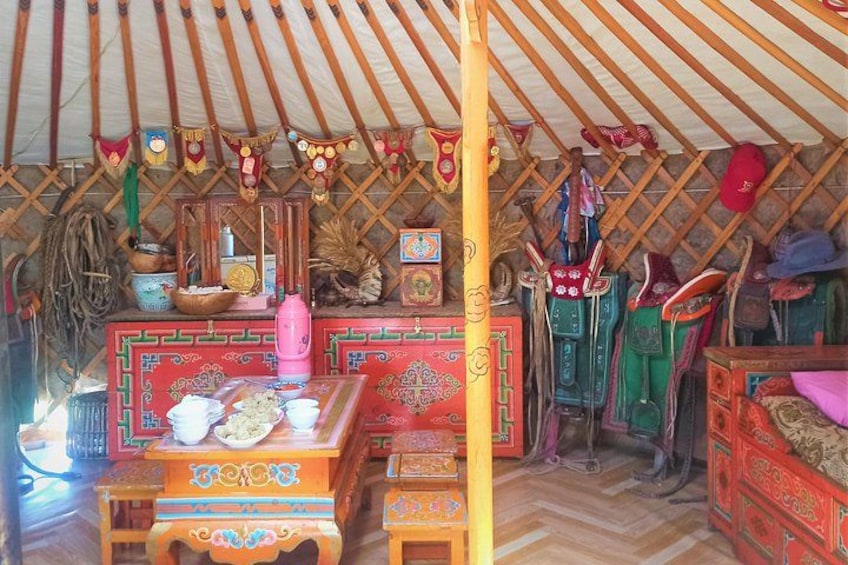 A traditional yurt interior with colorful decorations, a wooden table with bowls, and various textiles. 3