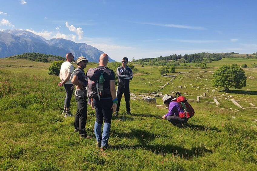 A group of people in a grassy field with mountains in the background. 1