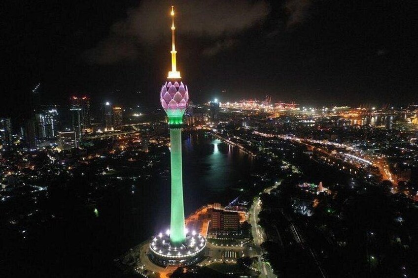 A cityscape at night with a prominent tower featuring a spherical structure at its base and a spire at the top. 2