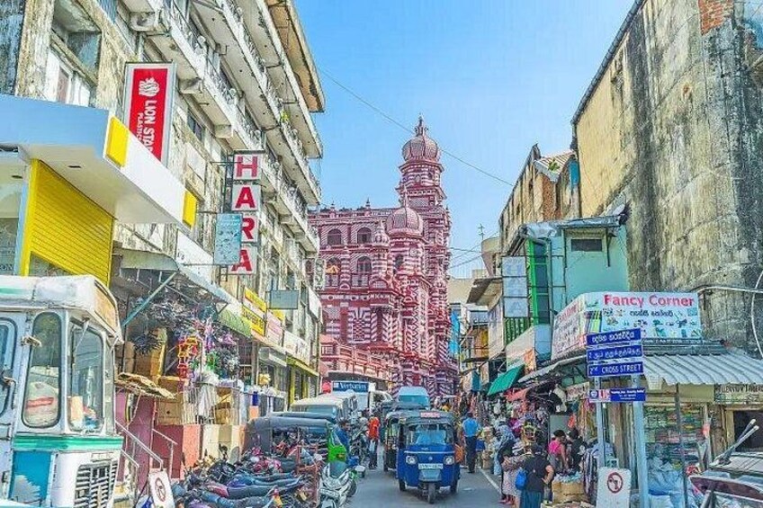 A busy street with shops, a prominent temple, and a sign for Fancy Corner. 5