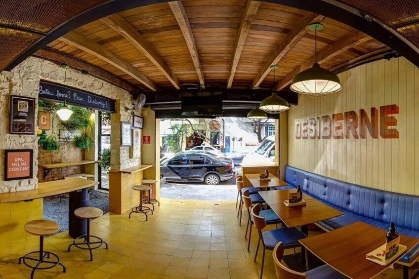 Un restaurant intérieur avec des poutres en bois, un coin salon bleu et une voiture garée à l’extérieur. 2