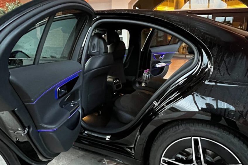 A car interior with a black leather seat, a door with a blue accent, and a visible gear shift. 2