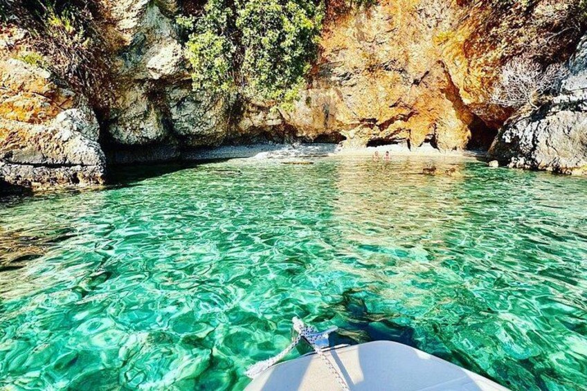 Ein Boot auf klarem türkisblauem Wasser, umgeben von steilen Felsen. 1