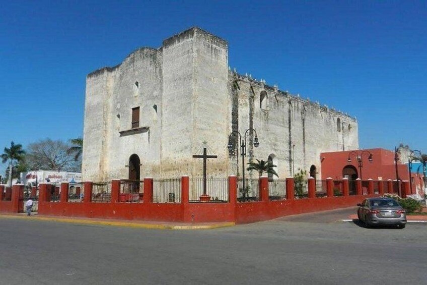 A historic building with a red fence, a cross, and a clear blue sky. 4