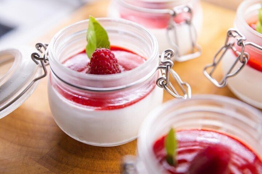 A close-up of a dessert in a glass jar with a metal clasp lid, garnished with a raspberry and a leaf. 2