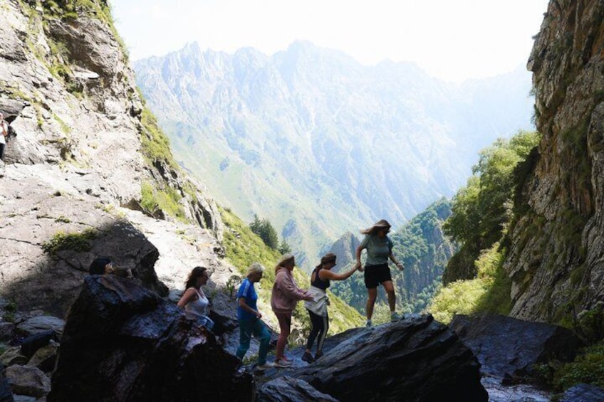 A group of hikers on a rocky mountain trail with a mountainous landscape in the background. 5