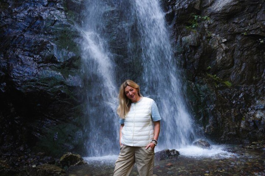 A person standing in front of a waterfall in a rocky area. 4
