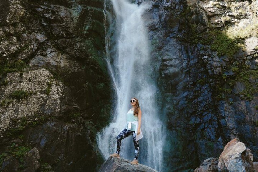 A person standing on a rock by a waterfall. 1