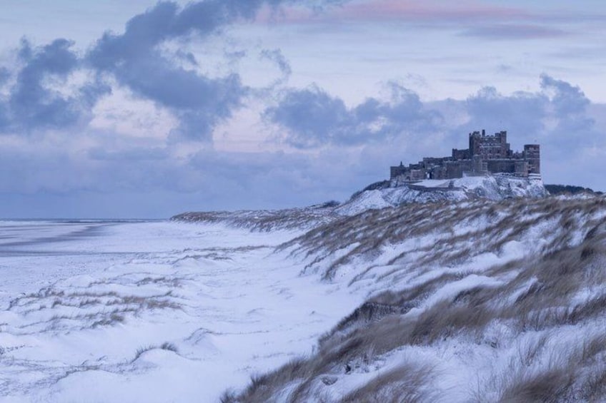 A snow-covered landscape with a castle-like structure on a hill. 1