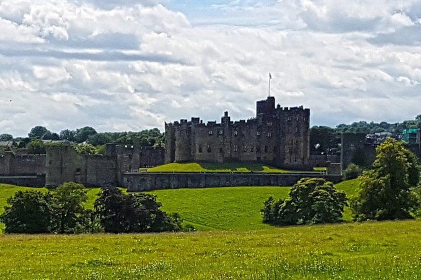 A historic castle with a grassy foreground and a cloudy sky. 3