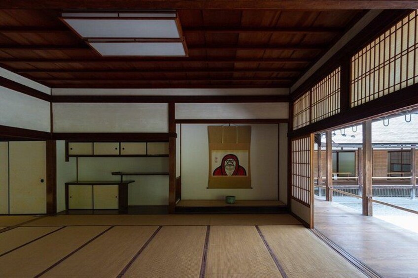 A traditional Japanese room with tatami flooring, sliding doors, and a painting on the wall. 2