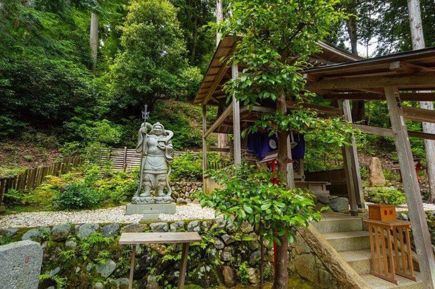 A stone statue, wooden structures, and lush greenery in a garden setting. 5