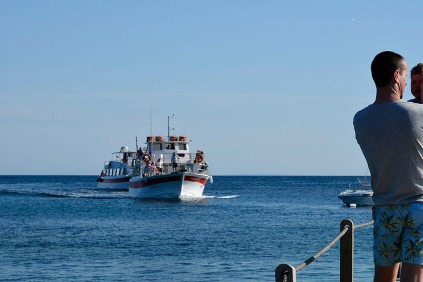 A boat with passengers, another boat in the background, and a person standing by the railing. 4