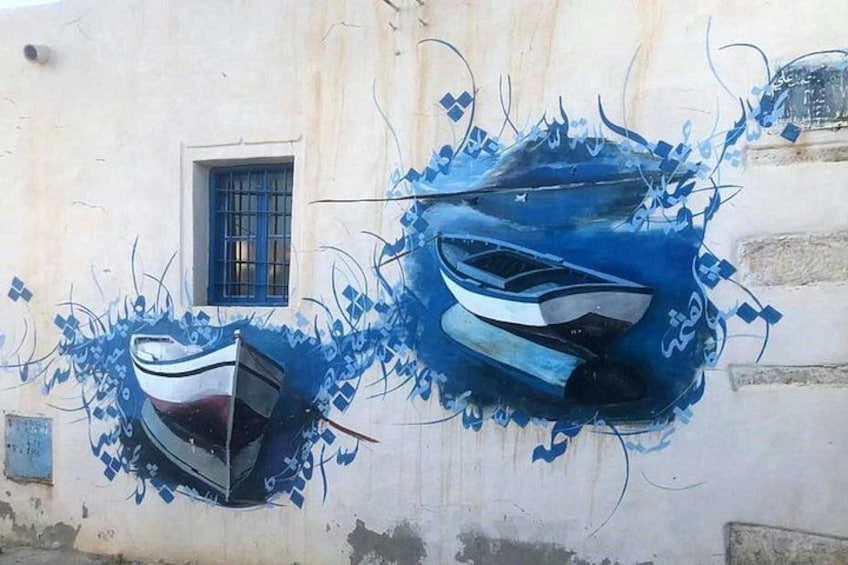 A wall with two boat murals, one larger and one smaller, both in blue. 1