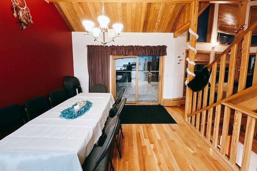 A wooden interior with a dining table, chairs, a chandelier, and a staircase. 5