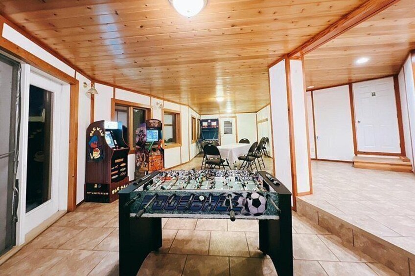A foosball table in a room with wooden floors and walls, a door, and a window. 4