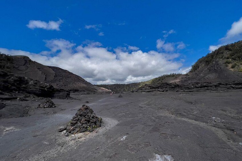 A volcanic landscape with a clear sky, a small pile of rocks in the foreground, and a barren terrain. 5