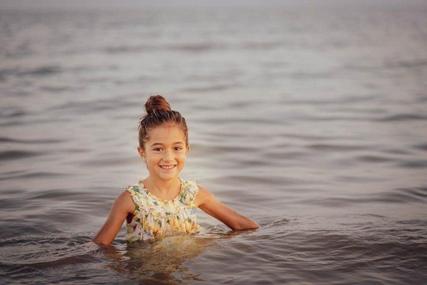 A person in a floral dress standing in calm water. 4