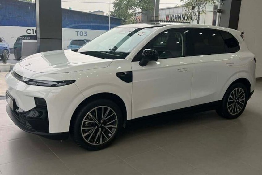 A white SUV with alloy wheels parked indoors, likely in a showroom. 2