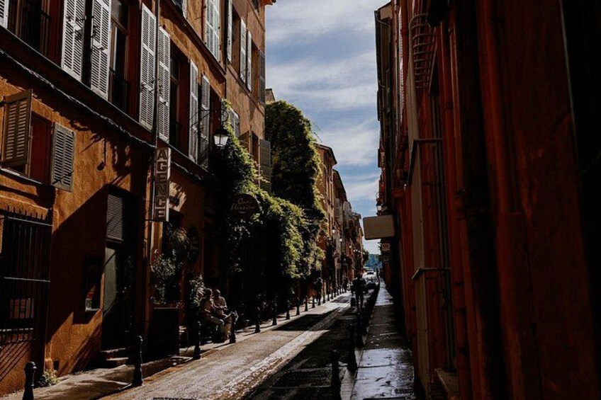 Una calle estrecha flanqueada por edificios, pavimento mojado y cielo despejado. 4