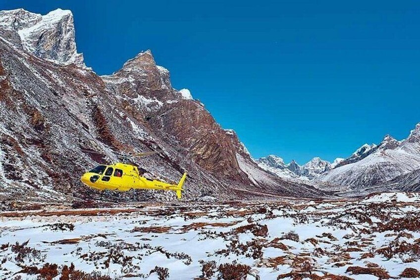 A yellow helicopter in a snowy mountainous area. 2