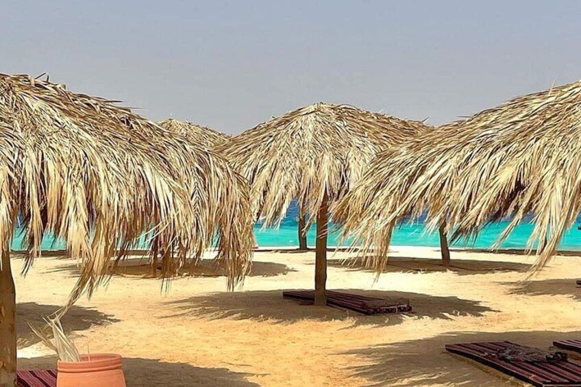Una playa con sombrillas de paja y bancos de madera. 2