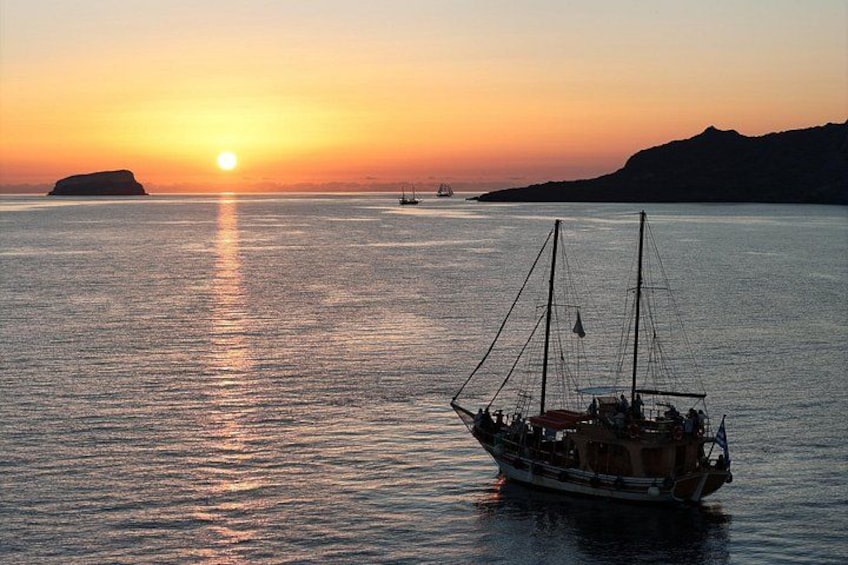 A sailboat on calm water during sunset with a distant island and a clear sky. 2