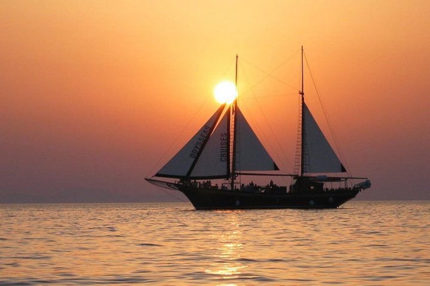 A sailboat with two sails on the water during sunset. 1