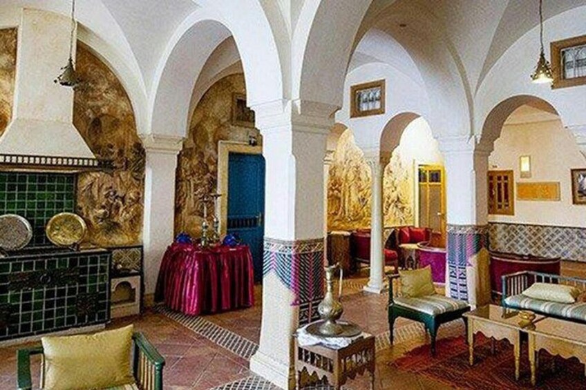A room with arches, a table with a red cloth, and a chair with a cushion. 5