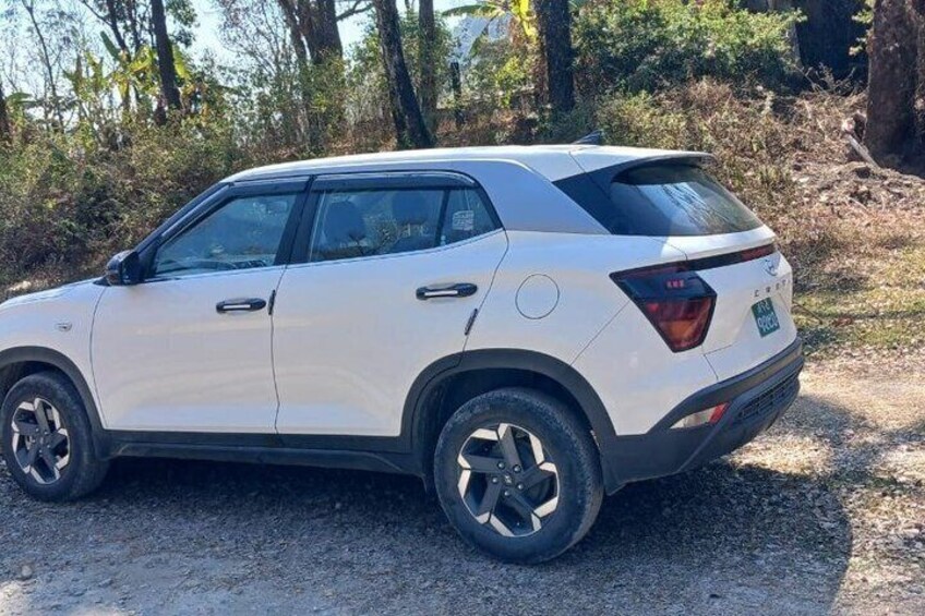 Un SUV blanco estacionado en un camino de grava bordeado de árboles. 2