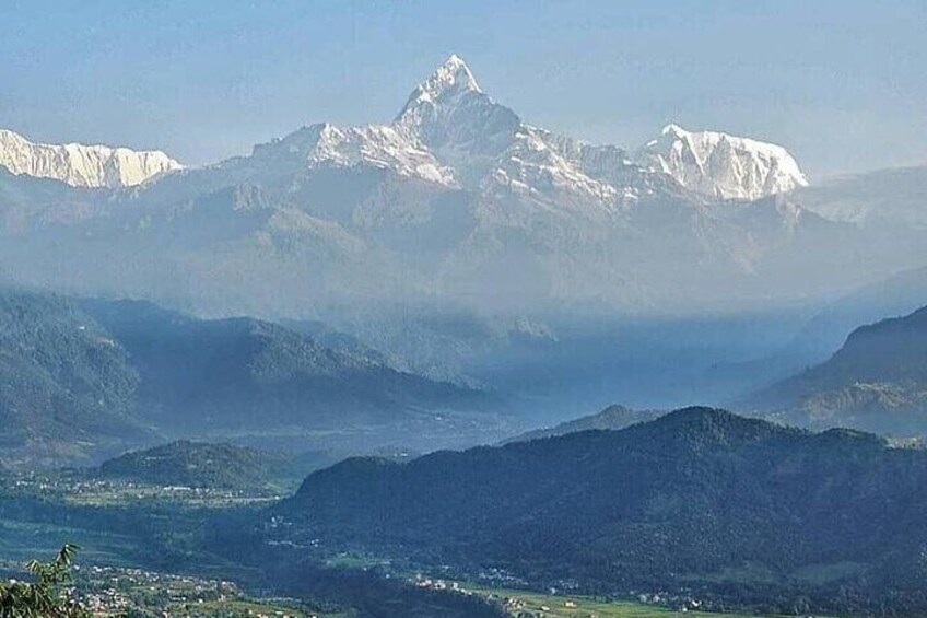 Una cordillera con picos nevados, un valle y un pueblo distante. 4