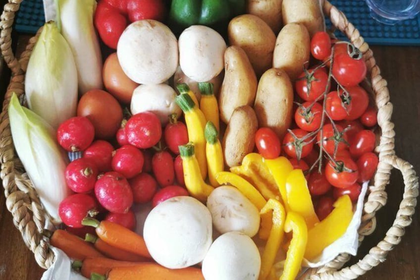 A basket filled with various vegetables including carrots, tomatoes, and bell peppers. 2