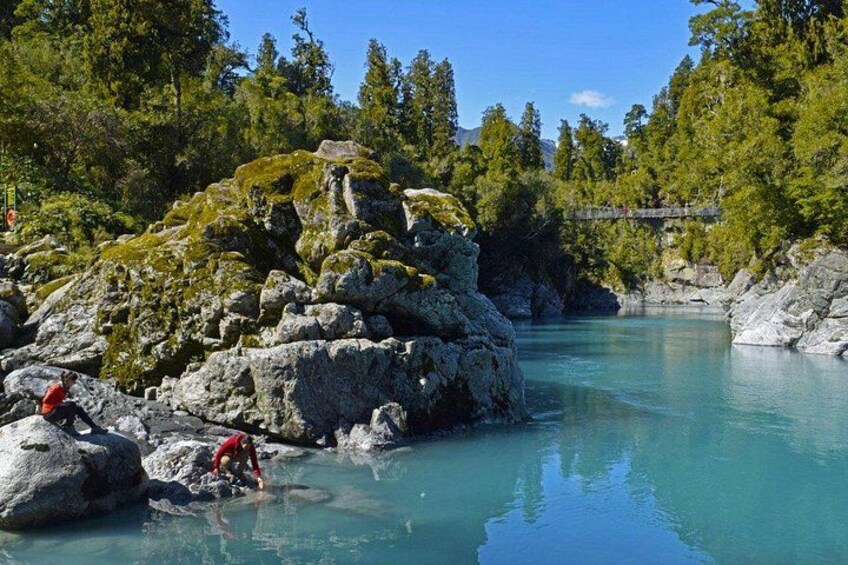 A river with clear water, surrounded by large rocks and trees. 2