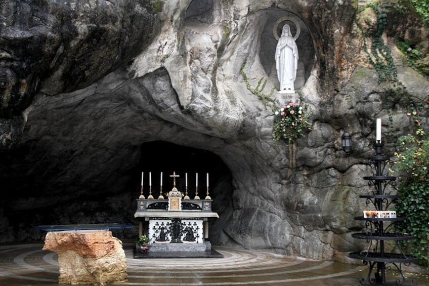 L’intérieur d’une grotte, avec une statue, un autel et des bougies. 3