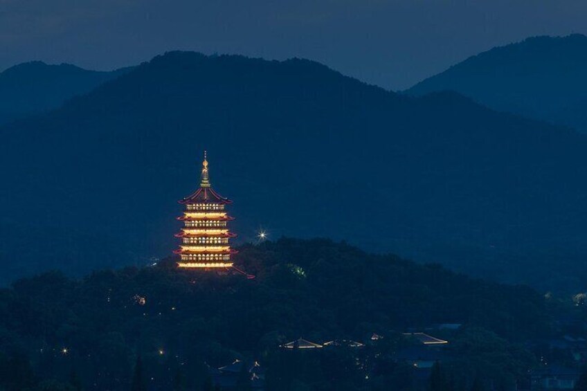 A pagoda illuminated against a mountainous backdrop. 5