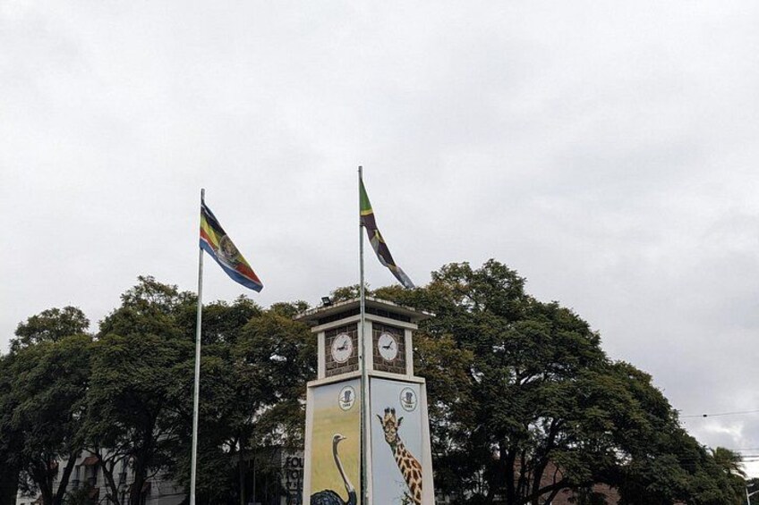 Una torre de reloj con dos banderas, rodeada de árboles. 4