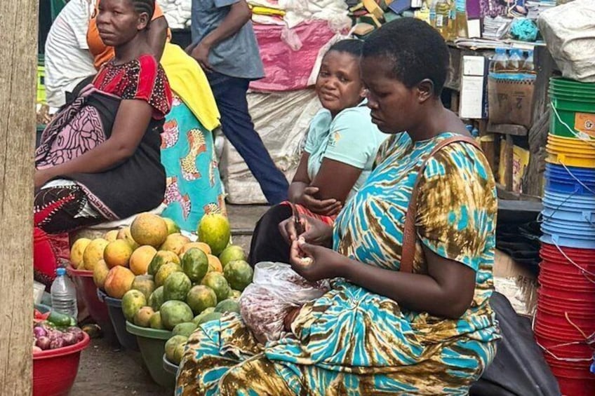 People at a market with fruits and plastic containers. 5