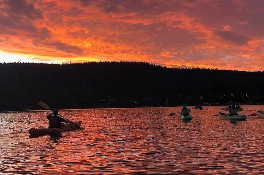 Kayakisti su un lago al tramonto, con una collina boscosa sullo sfondo. 5