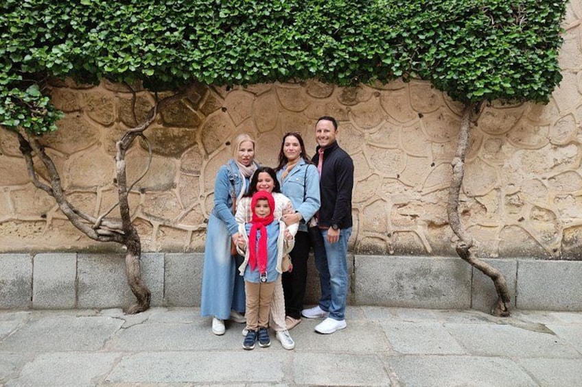 Un grupo de personas de pie frente a un muro de piedra con vegetación. 4