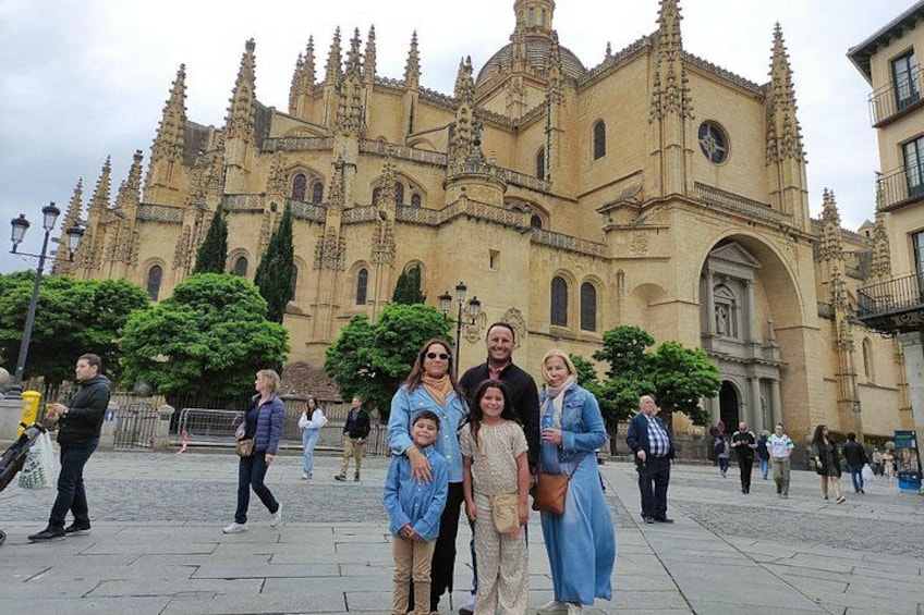 Un grupo de personas posando frente a una catedral grande y ornamentada con una torre de reloj. 1