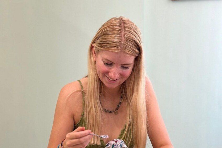Eine Person mit langem, blondem Haar, gekleidet in ein grünes Oberteil, hält eine Gabel mit Essen. 5