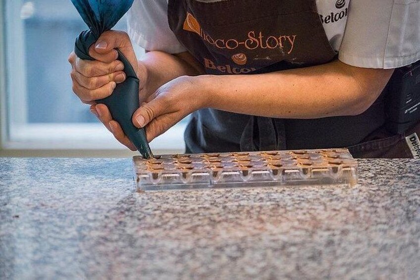Una persona usa una sac à poche per applicare glassa su un vassoio di cioccolatini. 3